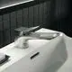 Waschtischarmatur in Chromoptik von Ideal Standard, mit einem flachen Hebel und passendem Waschbecken, vor einer schwarzen Kachelwand platziert.